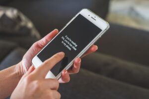 Personne interagissant avec un smartphone à l'intérieur, mettant en avant la technologie tactile et la communication.